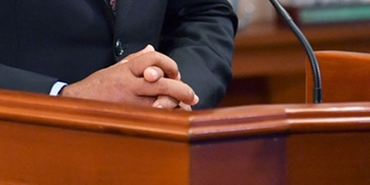 Hands resting on the lectern during the address.
